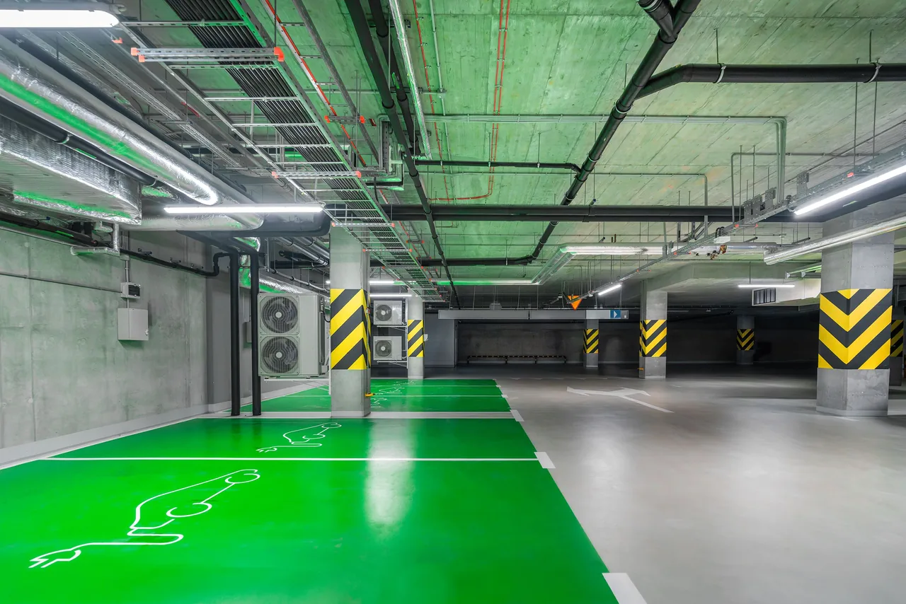 Green coated parking bays beside a grey vehicle lane in an indoor car park