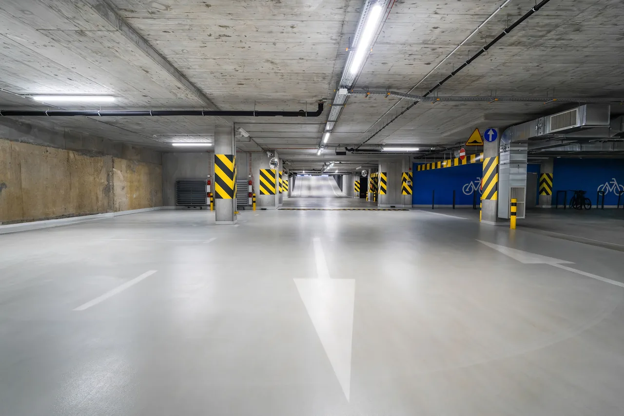 Grey coated garage floor with parking spaces and overhead lighting