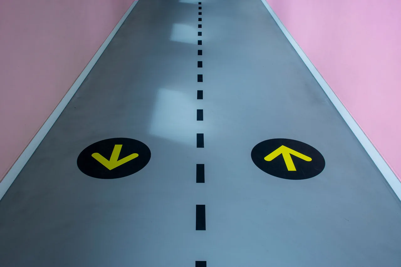 Smooth grey corridor floor with yellow arrows and a dashed centre line